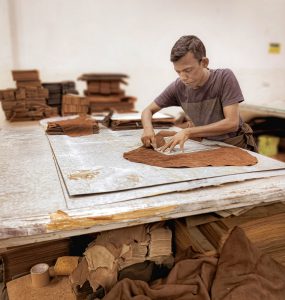 artisan is working on leather sheet